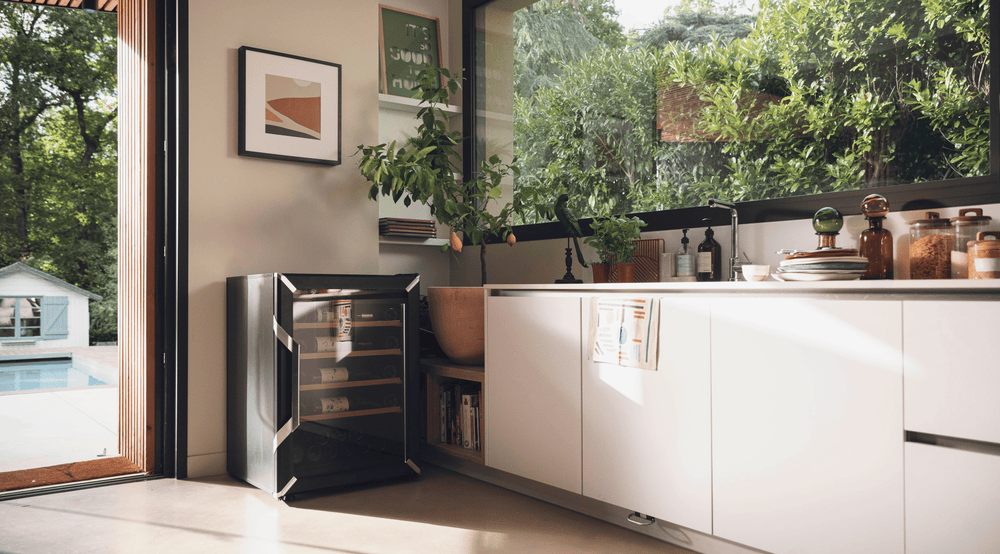 Goguette wine fridge small single zone 50 bottle capacity, black side view on a beautiful kitchen with big windows and doors.