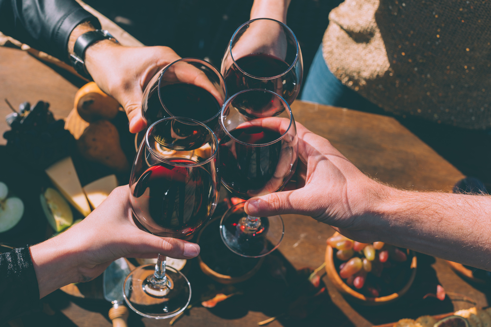 Four people toasting four glasses of red wine
