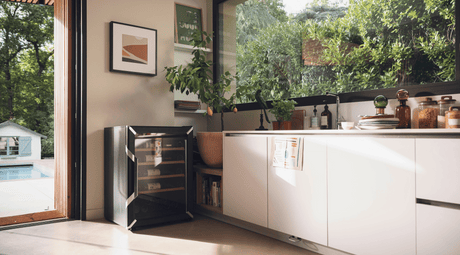 Goguette wine fridge small single zone 50 bottle capacity, black side view on a beautiful kitchen with big windows and doors. 
