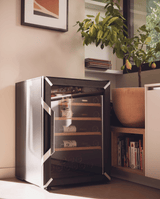 Goguette wine fridge small single zone 50 bottle capacity, black side view in a beautiful apartment next to a plant. 